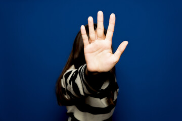 Stop violence against women. A brave teenager making a stop sign in the fight against violence. Isolated on blue background