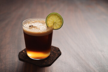 Espresso tonic in simple glass on walnut wood table with copy space