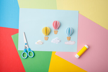 Colorful handmade paper balloon and cloud composition with tools on bright background ideal for toy...