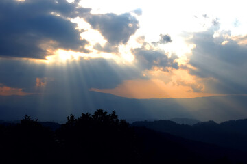 Sun ray of sun light shining down on cloud and sky with silhouette dusk and twilight on the valley mountain