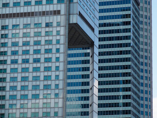 Modern blue glass skyscraper reflecting sunlight with geometric window pattern against urban skyline