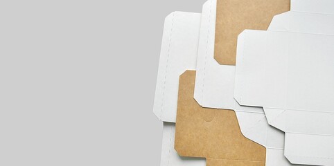 Fototapeta premium Paper box sheets. Opened cardboard boxes. Cardboard box layers background. Monochrome background, copy space. Sustainable packaging, artistic background. Transportation, packaging materials