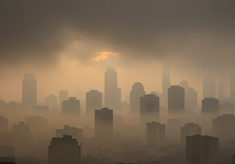 Naklejka premium A misty view of a city skyline enveloped in fog during dusk, highlighting the silhouettes of tall buildings and a mysterious atmosphere.