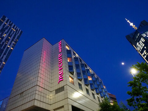 Modern Hotel Building with Pink Vertical Mercure Signage and Angular Architecture at Night