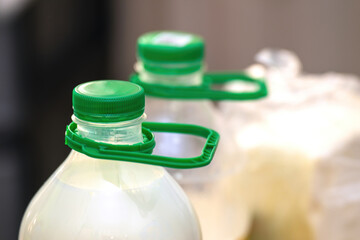 Green plastic handle attached to a large milk bottle for easy carrying, practical and ergonomic design for everyday use
