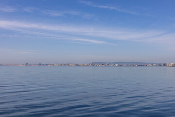 Calm sea with distant city skyline under clear blue sky in Sveti Vlas, Bulgaria.