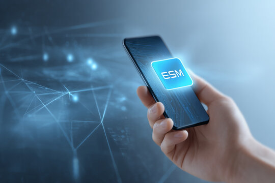 Hand holding smartphone displaying ESM digital icon on screen, technological background suggesting data connectivity and mobile app concept