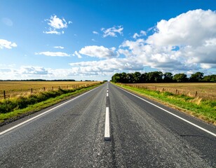 Fototapeta premium Open Road Stretching Through Wide Fields Under Bright Blue Sky