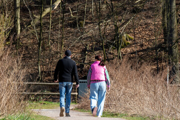 A man and woman are walking on a path in the woods