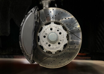 Car ventilated front brake disc with gray caliper. Modern brake disc with ventilation holes and...