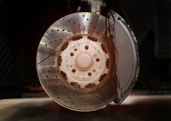 Car ventilated front brake disc with gray caliper. Modern brake disc with ventilation holes and...