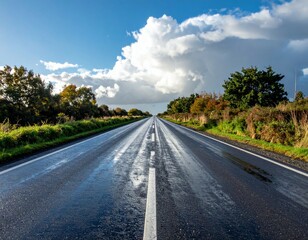 Obraz premium Serene Open Road Under a Vast Blue Sky with Fluffy White Clouds