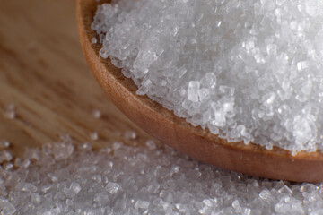 Crystal clear white sugar crystals macro close-up, spoon and wooden cutlery