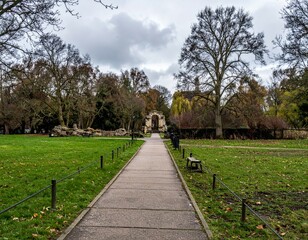 Serene Pathway Through Green Park Surrounded by Trees and Clouds
