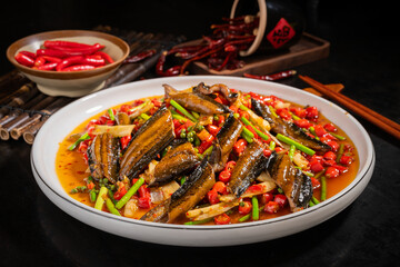 Chinese food spicy eel served on a white plate, dark kitchen background