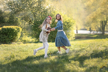 Mother and daughter are running in the park. They're having fun, messing around, playing with each...
