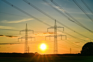 Fototapeta premium Power poles in spring, sunset, in the field and on the meadow, Brandenburg, Germany