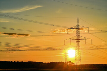 Fototapeta premium Power poles in spring, sunset, in the field and on the meadow, Brandenburg, Germany