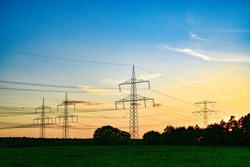 Power poles in spring, sunset, in the field and on the meadow, Brandenburg, Germany