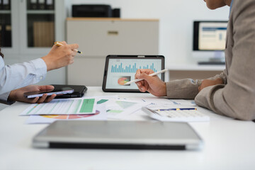 Business documents on office table with smart phone, tablet and laptop computer and graph with social network diagram and two colleagues discussing data in office.