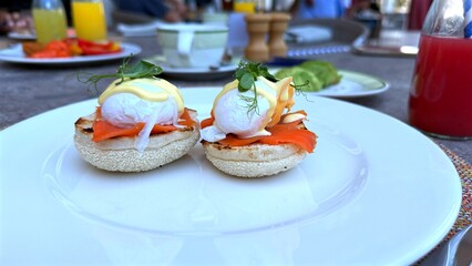 Poached eggs rest over smoked salmon and English muffin, creamy yolk melts into warm base, salmon...