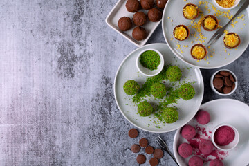 Assorted chocolate sweets with different sprinkling on ceramic plates. Handmade dessert for a holiday. Top view. Copy space