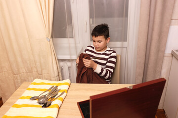 Boy wipes forks and kitchen knives. Housework.