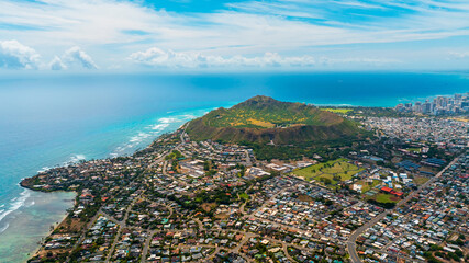Multiple houses are built in the green valley. Diamond Head Crater and high-rise skyline at backdrop. Aerial perspective on Honolulu, Hawaii, USA.