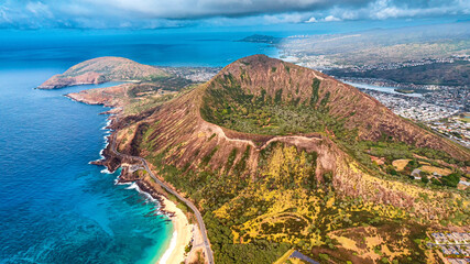 Lush greenery inside the crater. Flight over the top of Diamond Head Crater in Honolulu, Hawaii, USA. Blue waterscape and sky merging at backdrop. © Vadim