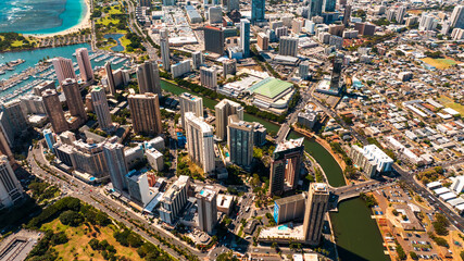 Approaching beautiful buildings of Waikiki on lovely sunny day. Ala Wai Canal on the left and yacht club on the right. Aerial view.