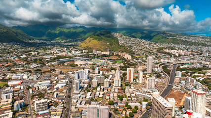 Varied urban landscape of densely-built Honolulu, Hawaii, USA. Aerial perspective eon the city under the grey cloudy sky.