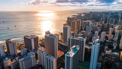 Obraz premium Cityscape of Waikiki, Hawaii, USA in the dusk time. Setting sun reflects on the waterscape of the ocean. Aerial view.