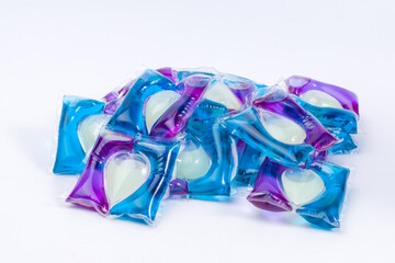 A pile of blue, purple and white laundry gel capsules. Top view.