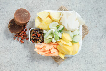 Mixed fruit and vegetable in plastic container on concrete background, top view
