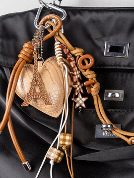 close up of brown bag trim, heart shaped keychains, eiffel tower keychains and beaded cord on black bag