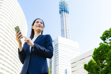 街でスマホを使う女性ビジネスパーソン