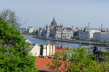 Panoramic view of Budapest city with Parliament building, Danube River, bridges and green trees under clear blue sky