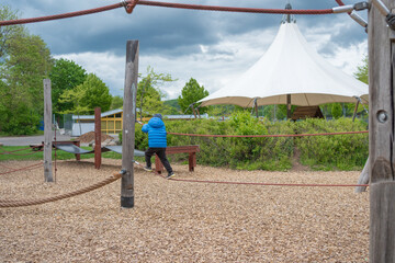 Fototapeta premium Child Playing on Adventure Playground Under Cloudy Sky