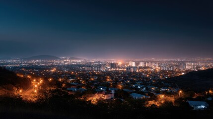 Obraz premium Beautiful panoramic shot of a city illuminated by thousands of street lights at night, with the glow of buildings creating a captivating skyline
