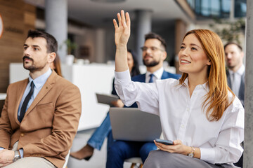 Female manager rising hand during the seminar and asking questions.