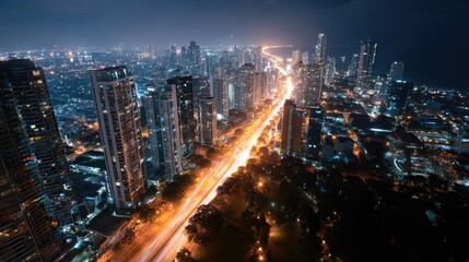 Fototapeta premium Overhead view of a glowing cityscape at night, with roads and streets filled with shimmering street lights, and tall buildings lit up against the dark sky