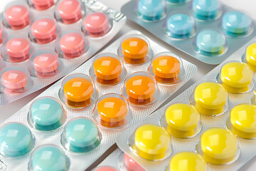 Colorful Blister Packs of Pills in Shades of Pink, Blue, Orange, and Yellow Arranged Neatly on a White Background