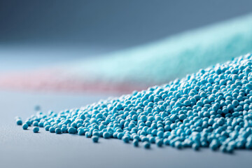 Fototapeta premium Layered mounds of blue polymer pellets in close-up on light background
