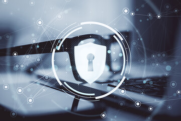 Cybersecurity shield icon overlaying blurred glasses and laptop on desk background with abstract network connections and digital light elements.