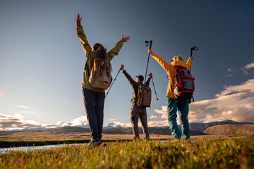 View from below of tourists in the mountains standing on the river bank and raising their hands, low angle view