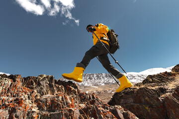 Bottom view of male trekker stepping from rock to rock in mountains on sunny day, low angle view