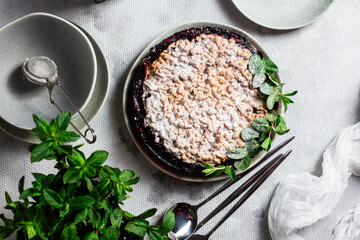 Round Pie with black currants and mint in a plate on the table. Dessert