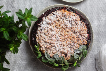 Round Pie with black currants and mint in a plate on the table. Dessert