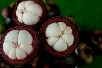 Fresh mangosteen fruits and cross section showing the thick purple skin and white flesh.