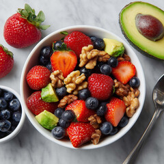 Obraz premium Strawberry, blueberry, avocado and walnut fruit salad in white bowl on marble table, top view